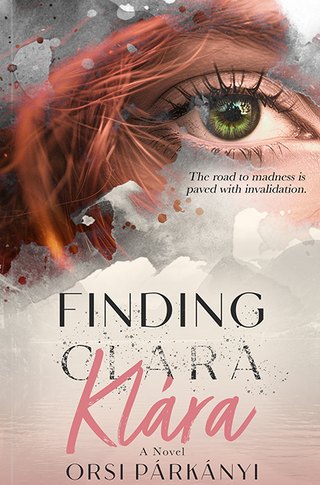 Finding Klára book cover — a green eye looking out from behind windblown copper hair and charcoal ink splatter, above misty mountains. The name Clara is struck through and rewritten below in rose script as Klára.